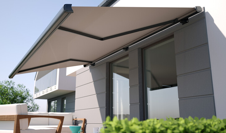 Ausfahrbare Markise über einer Terrasse mit Sitzmöbeln an einem modernen Haus.