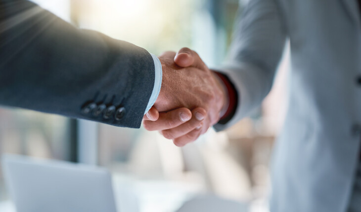Nahaufnahme eines Händedrucks zwischen zwei Personen in Businesskleidung.