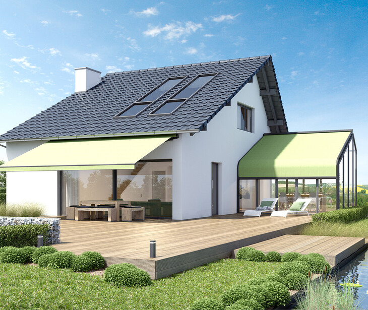 Modernes Einfamilienhaus mit Satteldach, großen Fenstern, zwei grünen Markisen und Holzterrasse am Wasser.